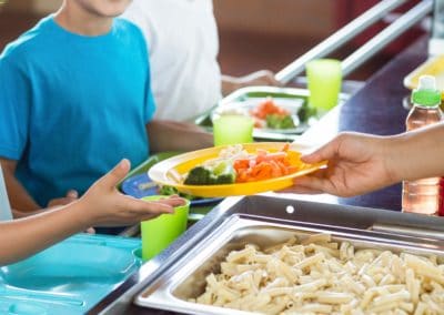 cropped,image,of,woman,serving,food,to,schoolchildren,in,canteen