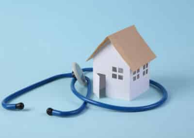 mini,paper,home,figurine,and,stethoscope,on,a,blue,background.