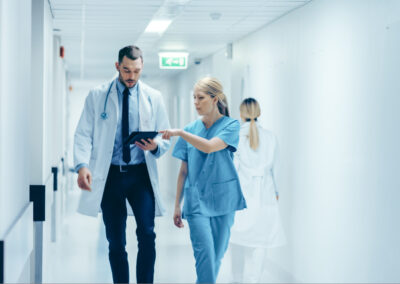 female,surgeon,and,doctor,walk,through,hospital,hallway,,they,consult