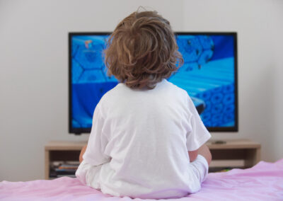 little,boy,sitting,on,bed,watching,television.